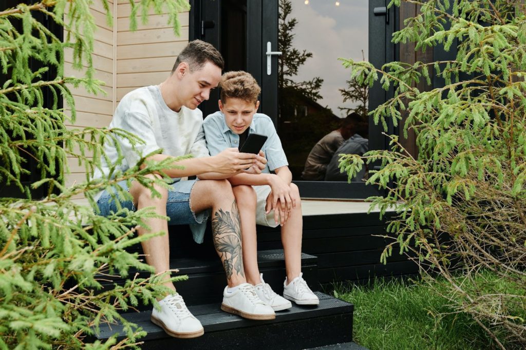 Father and son sitting on front steps of the house reading about the importance of having a will